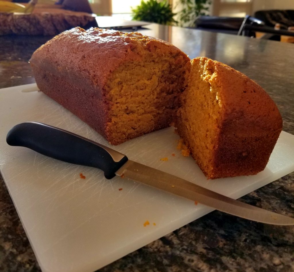 Picture of a loaf of pumpkin bread with a quarter sliced off so you can see inside.